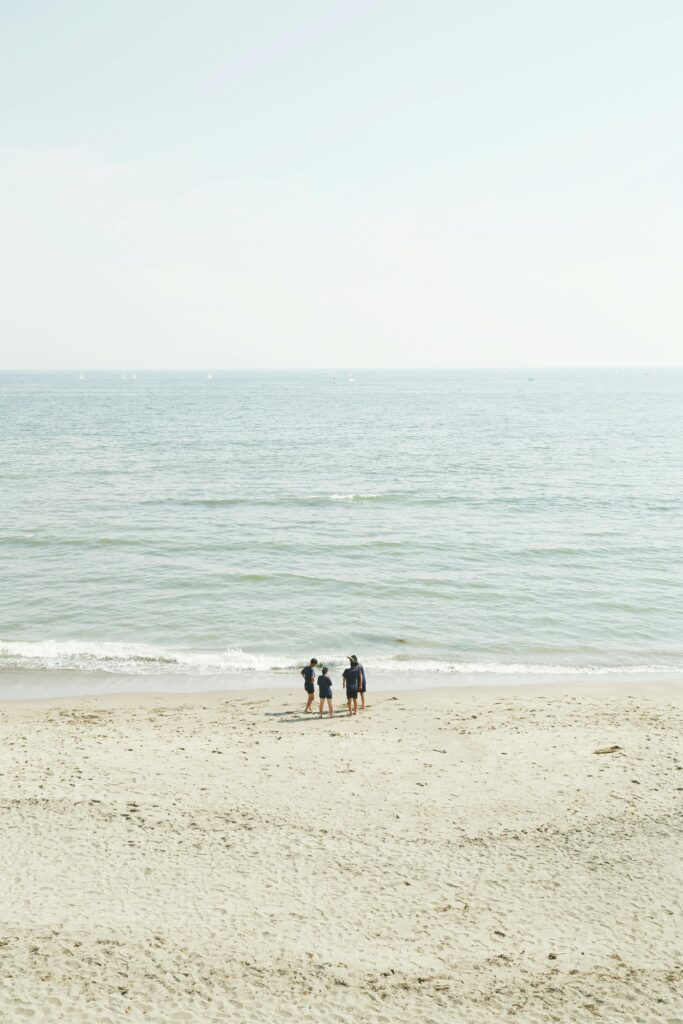 A serene scene of a family walking on a sandy beach by the calm sea.